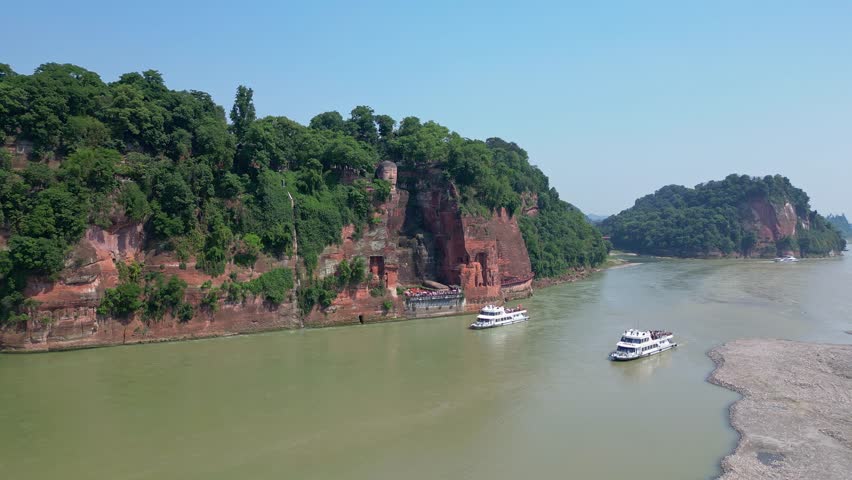 Leshan, China: Aerial forward drone footage of the famous Leshan giant Buddha stone statue that dates to the Tang dynasty at the confluence of the Min River and Dadu River in Sichuan in China.