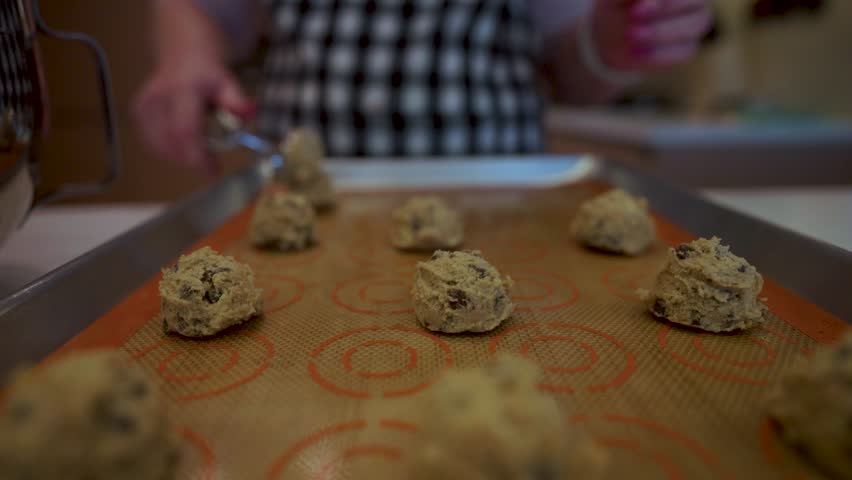 Kitchen Chef Using A Scoop To Put Cookie Dough On A Pan For Baking During Preparation Process.
