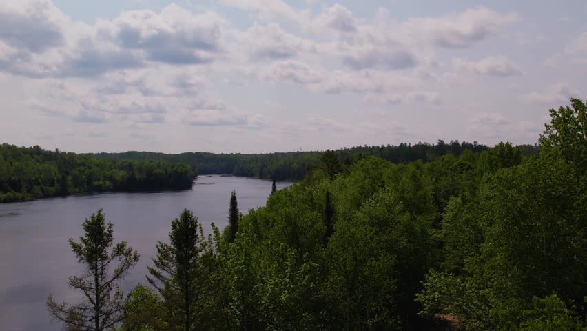 Panoramic aerial view of a wide, flat expanse of water on the Gatineau River bordered by forests.