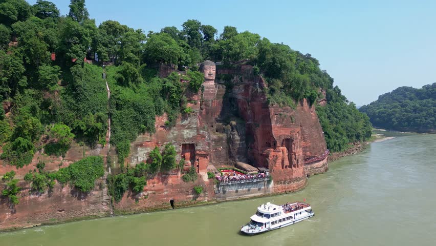 Leshan, China: Aerial drone footage of the famous Leshan giant Buddha stone statue on the Min River with tour boats in Sichuan in China. Shot with an upward motion