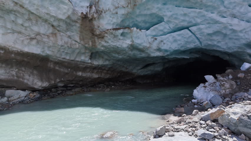 Serene glacier cave with blue ice, flowing stream evokes awe and solitude