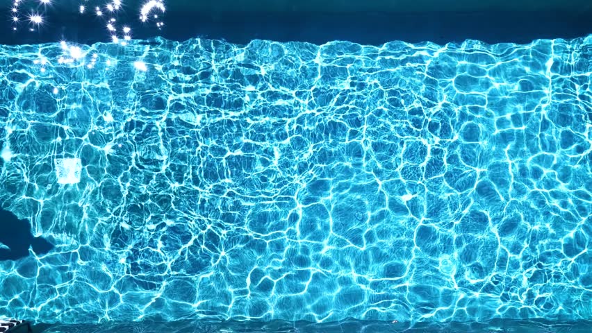 Aerial overhead slow motion view of a man jumping and diving into a swimming pool during summer time