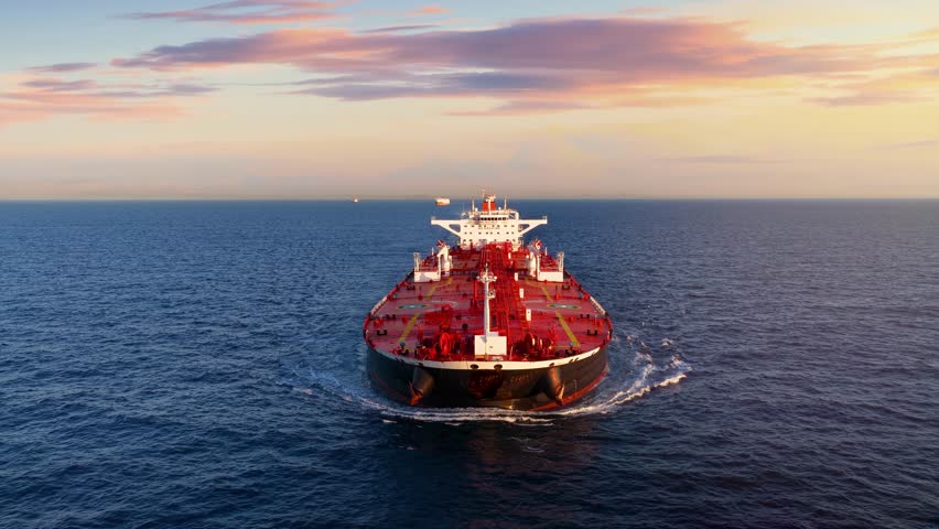 Aerial front view of a heavy loaded crude oil tanker sailing over open ocean during sunset time