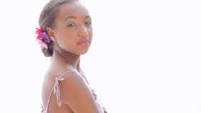 Young african american teenage girl wearing spring fresh rainbow eyeshadow and flowers in her hair, turning and smiling at camera against a light white background. - Powered by Shutterstock - Get 15% off with code: PIKWIZARD15
