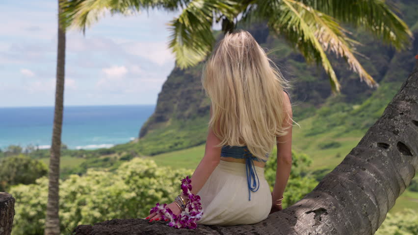 a woman in a Hawaiian national shirt wears a necklace with a wreath of flowers around his neck. A happy female tourist holds the national Hawaiian orchid and hibiscus necklace as a token of welcome