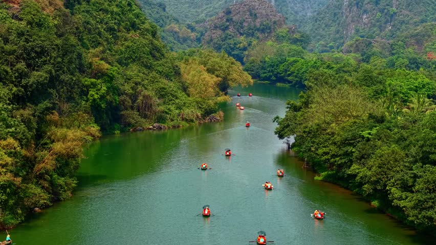 Scenic river journey at sunrise through lush mountains in Ninh Binh Vietnam, Tam Coc National Park.