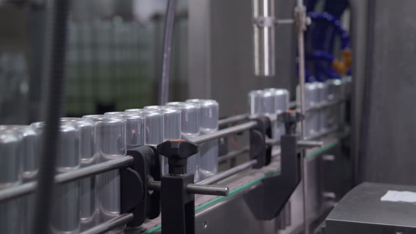 Empty aluminum cans on conveyor belt before branding and labeling, modern beverage production process in factory.
