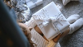 Soft looking woman resting on carpet, clutching white wrapped christmas gift, surrounded by festive decorations and steaming hot chocolate with marshmallows - Powered by Shutterstock - Get 15% off with code: PIKWIZARD15