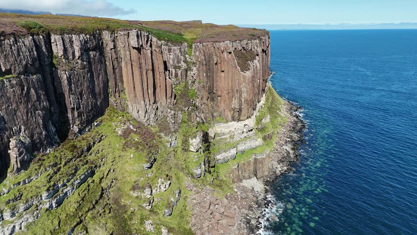 Aerial drone view of a dramatic rocky cliff over the ocean, with waves crashing on a wild stone beach. Scenic coastal landscape panorama, perfect for travel, nature, tourism and adventure concepts.