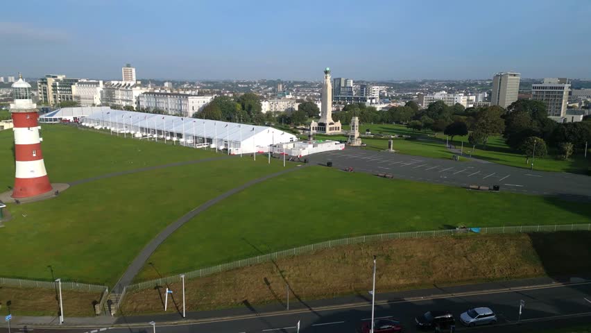 
Plymouth, Devon, England: DRONE VIEW: Track shot across Plymouth Hoe park showing Smeaton's Tower. Plymouth is a port and hosts the largest operational naval base in Western Europe (Clip 1 of 2).
