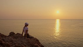 Young woman in casual wear and baseball cap sits peacefully, contemplating serene ocean horizon during early morning golden hour - Powered by Shutterstock - Get 15% off with code: PIKWIZARD15