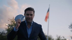 Portrait business man holding cash dollar bills front flag America. Big luck. Dollar cash money concept. Man hold cash money near flag usa. Financial luck and success. Businessman Holding Money - Powered by Shutterstock - Get 15% off with code: PIKWIZARD15
