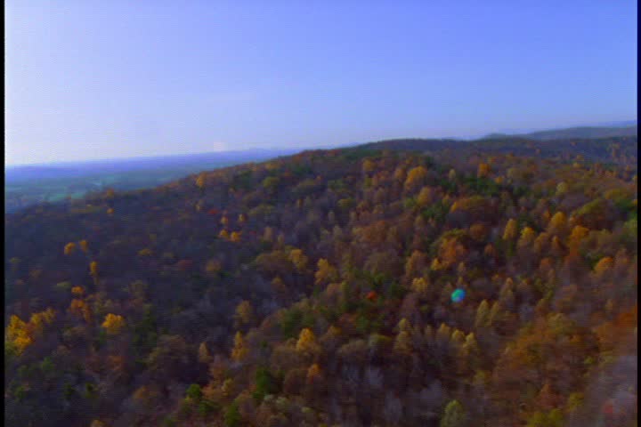MOUNT VERNON, VIRGINIA - CIRCA JANUARY 1992:Flight  Over treetops in the Virginia mountains in autumn. Trees are orange, gold and green under clear blue sky.