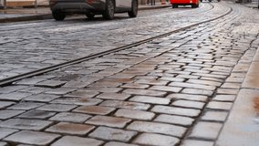 Feet walking on wet cobblestone street with tram track. Low-angle perspective capturing pedestrian walking across wet cobblestone street, tram track visible, passing cars blurring in urban background - Powered by Shutterstock - Get 15% off with code: PIKWIZARD15