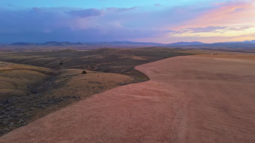 A scenic aerial view of the Montana Great Plains and prairie land at sunset, with vast open fields