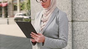Young Muslim woman in hijab using tablet on urban street outdoors - Powered by Shutterstock - Get 15% off with code: PIKWIZARD15