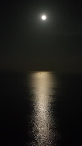 Crescent moon reflected in the calm relaxing sea in the night. Night scene. Vertical.