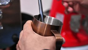 Close up of barista frothing milk in a metal pitcher, using a steaming wand in a coffee shop - Powered by Shutterstock - Get 15% off with code: PIKWIZARD15