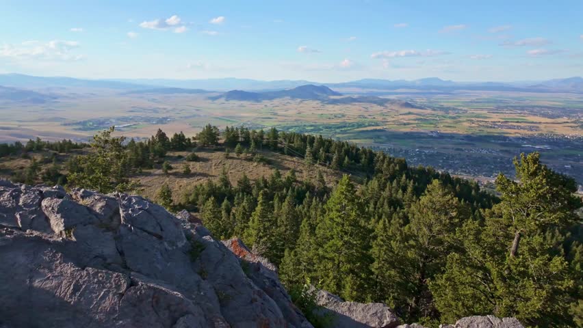 A panoramic aerial view of the city of Helena, Montana is captured at sunset, showcasing the urban landscape