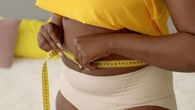 Woman measuring waist size at home while embracing a healthy lifestyle journey - Powered by Shutterstock - Get 15% off with code: PIKWIZARD15