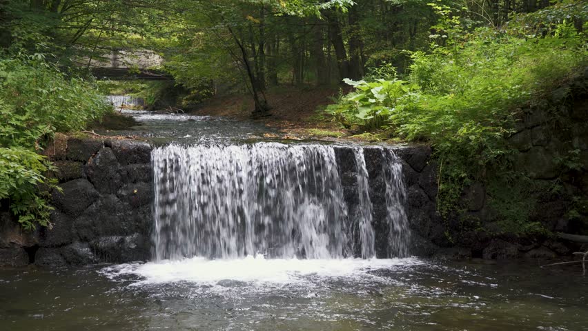 Hiking trail through lush forest leading to Sutovsky waterfall in Mala Fatra, Slovakia. Aerial view of small waterfall along the path. Scenic nature, perfect for travel and outdoor adventure themes