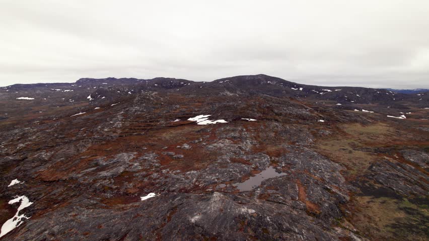 Dolly-in drone shot gliding over the vast Greenlandic tundra, showcasing icy plains, Arctic wilderness, and the pristine northern landscape.