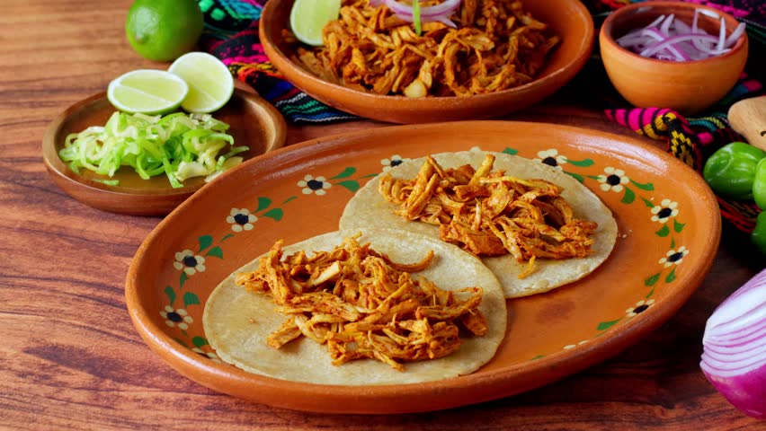 Mexican food, cochinita pibil, a hand is preparing tacos with shredded meat