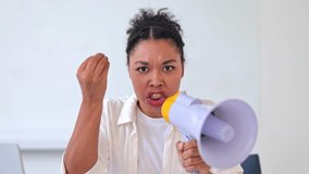Furious African American businesswoman wearing a white shirt shouts into a megaphone indoors, expressing strong emotions. Confident female leader making powerful statement. - Powered by Shutterstock - Get 15% off with code: PIKWIZARD15
