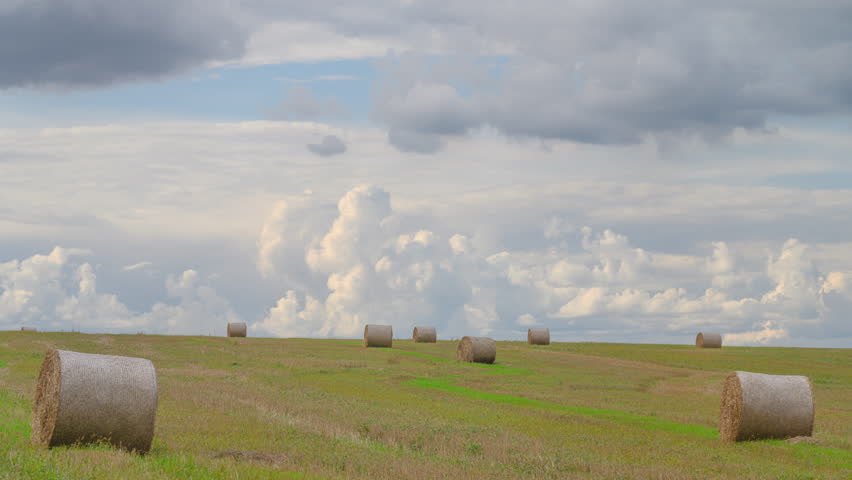 Serene and picturesque landscape featuring hay bales under a beautifully cloudy sky