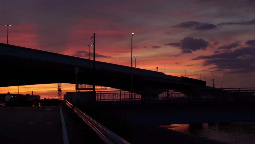 A beautiful sunset seen from the riverside. Silhouettes of cars and bicycles.