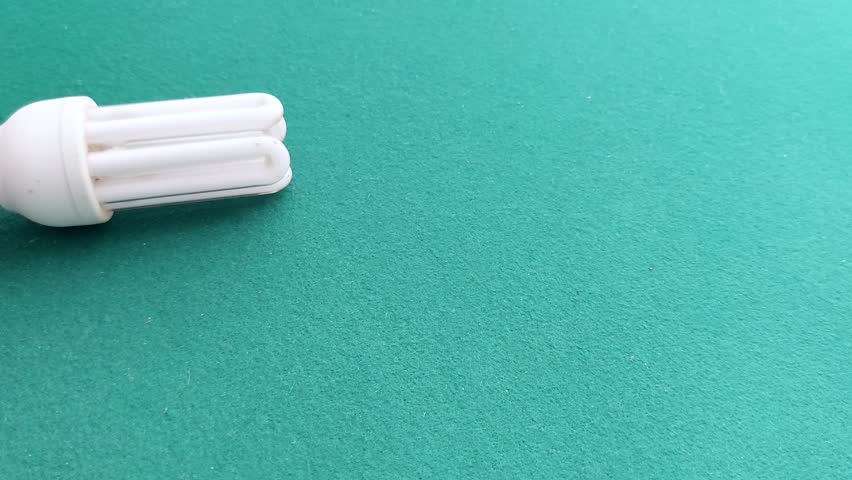 A hand holds a spiral CFL bulb against a green backdrop-highlighting energy-efficient lighting with a clean, minimal aesthetic. Timestamp suggests a timed demo or test