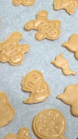 Festive homemade christmas cookies lying on baking paper, carefully arranged with seasonal shapes, waiting to transform in warm oven before holiday gathering
