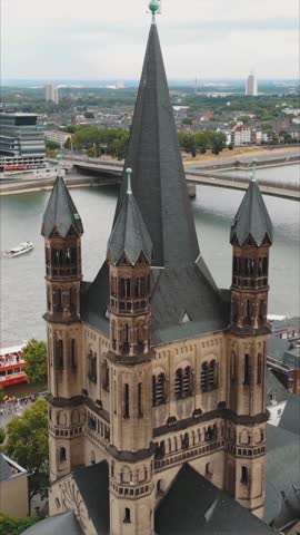 Aerial view of the Great Saint Martin Church, a Romanesque Catholic church in Cologne, Germany, with the Rhine river in the background. Vertical Video, orbit motion