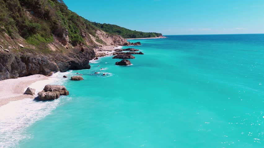 Aerial flying along idyllic tropical coastline with pristine turquoise water, white sand beaches, and rocky cliffs, Barahona, Dominican Republic