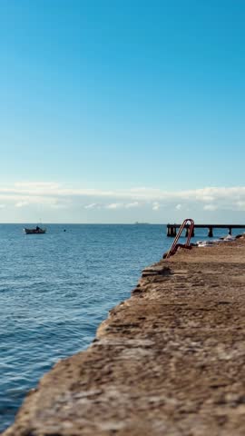 Stairs leading down to the beach and sea under a blue sky