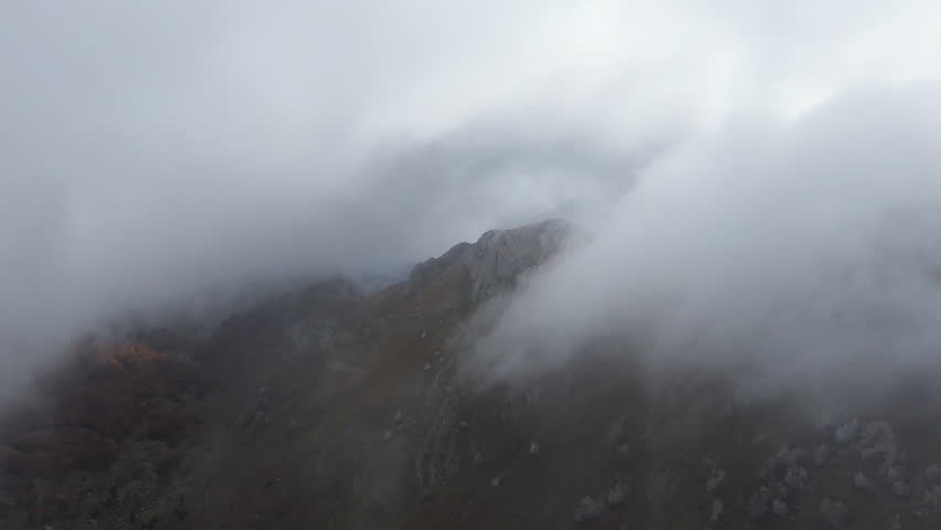 Mountain peak seen through heavy clouds The landscape is rocky Mist fills the air partially obscuring the view