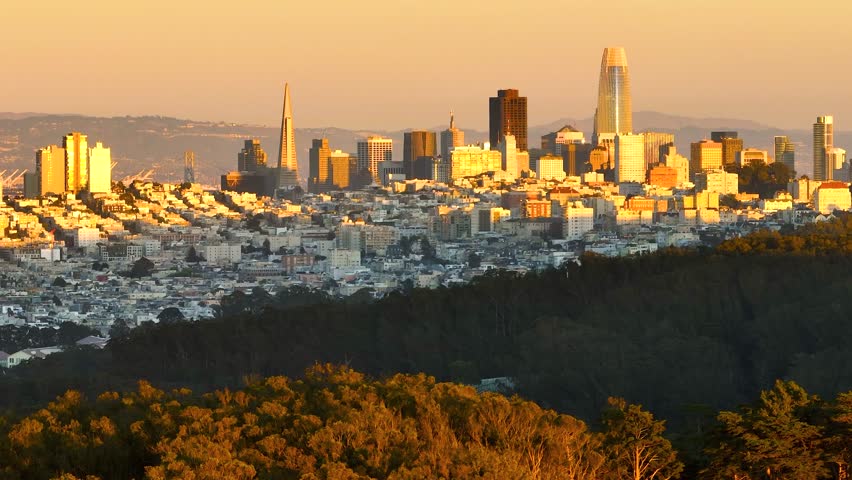 Aerial view of the iconic San Francisco skyline showing the Salesforce Tower and Transamerica Pyramid bathed in the warm glow of the setting sun, San Francisco, California, United States.