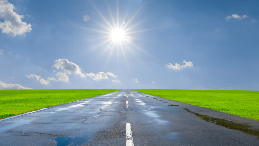 wet asphalt road among green fields under a sparkle sun time lapse scene