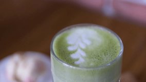 Green latte art Skilled barista mixing intricate matcha latte art, creating delicate foam pattern inside ceramic cup, accompanied by golden croissant on minimalist surface - Powered by Shutterstock - Get 15% off with code: PIKWIZARD15