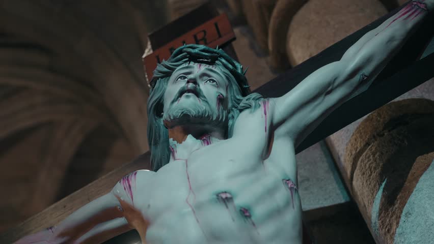 close up of crucifix statue showing christ with crown of thorns and wounds