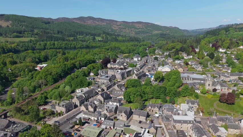Panoramic aerial view of Pitlochry village in Scotland, surrounded by lush green nature, forests, and highland landscapes