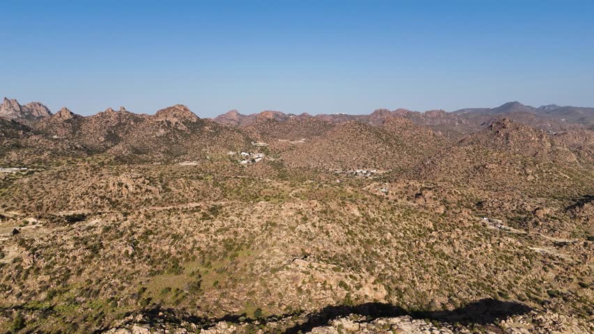 Drone flying over a dry landscape with rocky hills, sunny day in Saudi Arabia