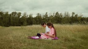 Boy and girl sitting on blanket drawing together in park. Children creating sketches while relaxing on green grass. Teenagers making drawings together outdoors in nature - Powered by Shutterstock - Get 15% off with code: PIKWIZARD15