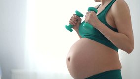 Fit mom-to-be performing controlled dumbbell exercises. Responsible approach to maintaining muscle tone during gestation period. - Powered by Shutterstock - Get 15% off with code: PIKWIZARD15