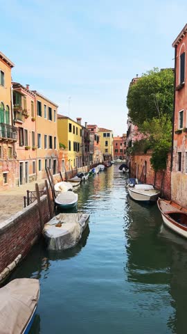 Old venetian architecture on the canal in Venice, Italy. Boats on the canal. Beautiful summer cityscape at sunny day. Famous travel destination. Vertical video
