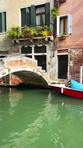 Old venetian architecture on the canal with bridge in Venice, Italy. Boats on the canal. Beautiful summer cityscape. Vertical video
