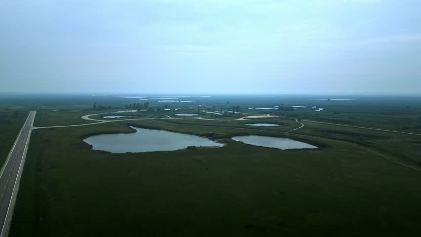 Blue sky with morning fog above wetlands; road lines trace the horizon