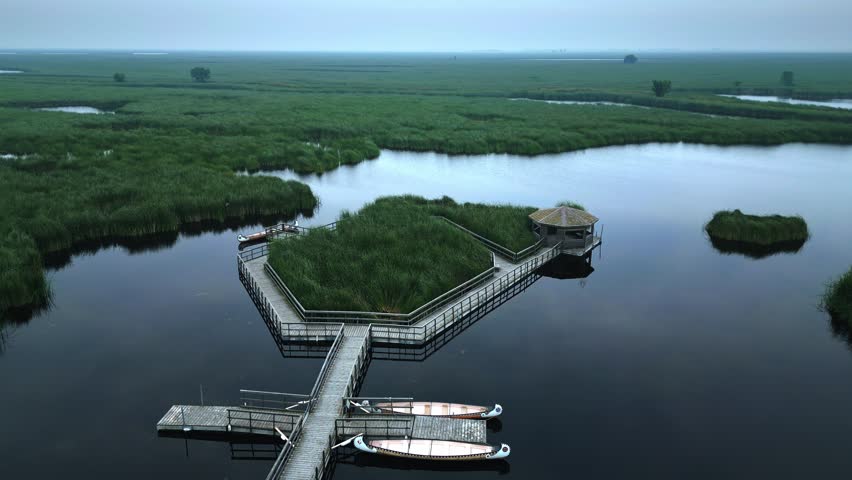 Drone circles boardwalk over marsh in fog with island gazebo