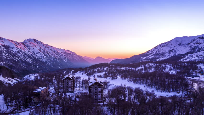 Hyperlapse of sunrise over snow-covered mountains in Santiago de Chile, with purple and orange tones coloring the winter landscape.