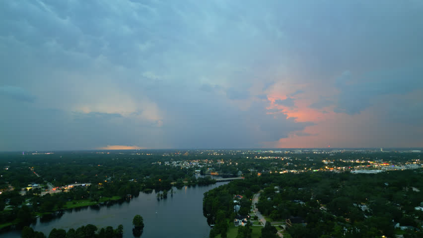 Aerial of storm clouds over Tampa glowing with yellow and orange flashes at sunset